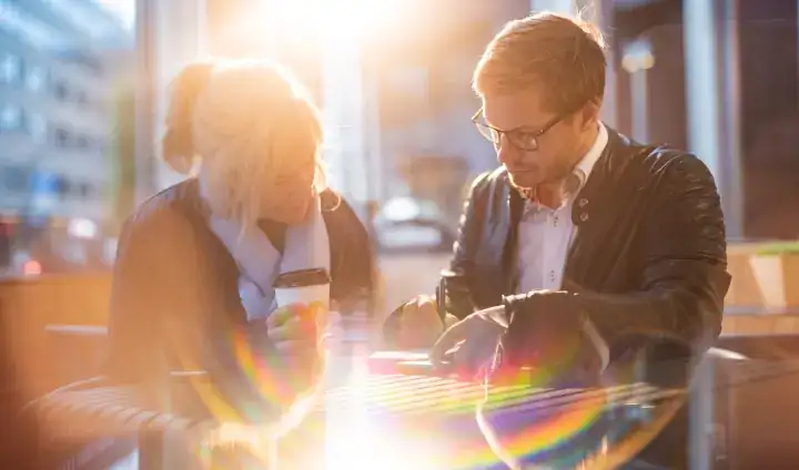 Highly stylized photo uses focal length, filters, and lens flare to dramatize two people working at an outdoor table