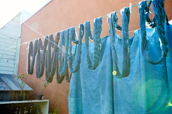 Indigo-dyed fabric and yarn hang to dry in the sun behind Vejar and Rodriguez’s textile shop.
